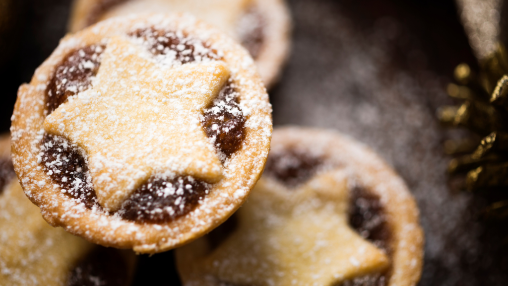 Image shows a plateful of all-butter orange mince pies with a star shaped top and sprinkled with icing sugar