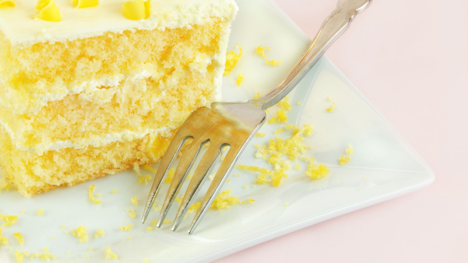 lemony lemon cake recipe. Image of a lemony lemon cake with a fork on a pink background