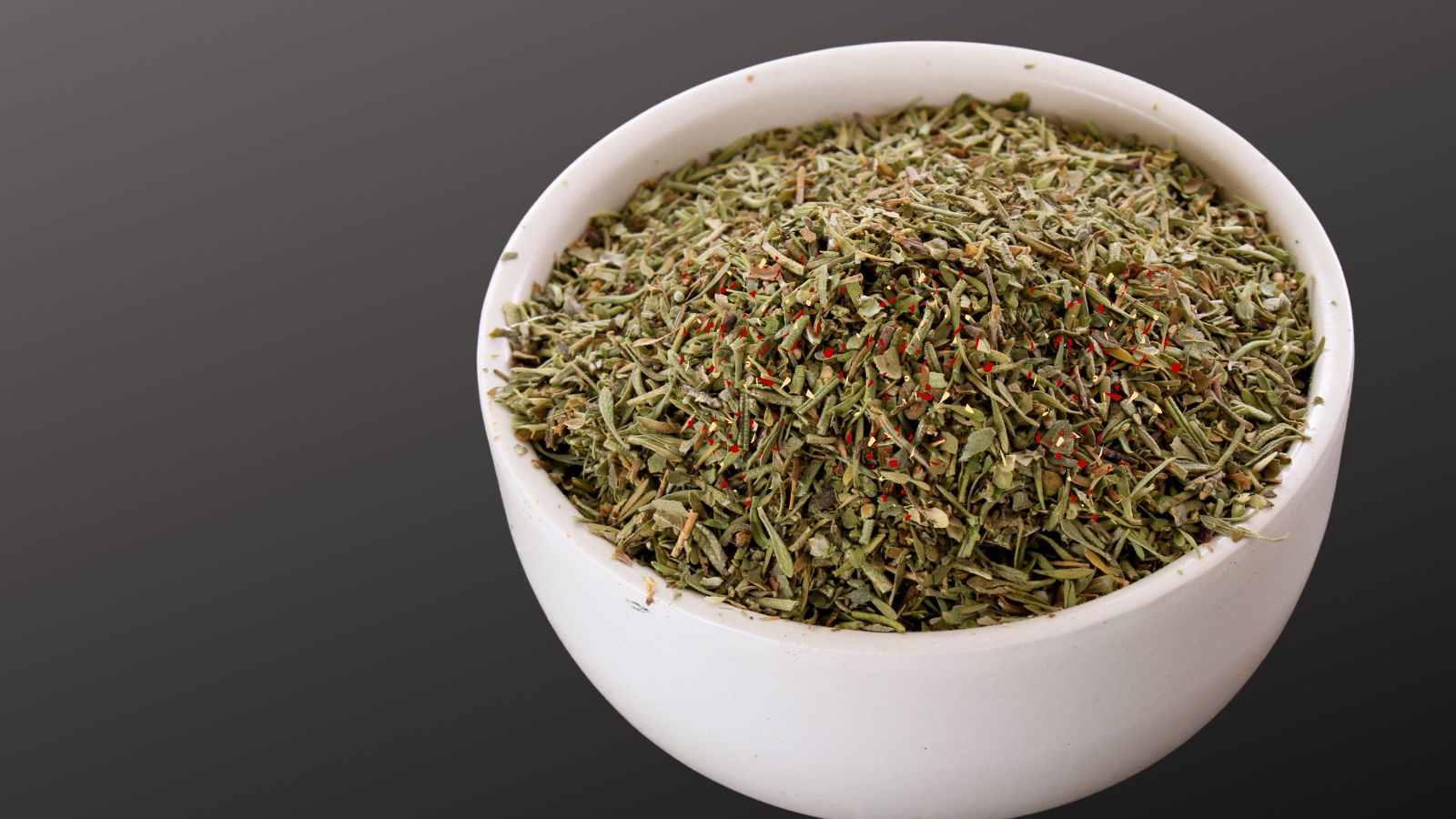 kitchen cupboard staples image of spicy italian seasoning in a white<br />
bowl on a grey background