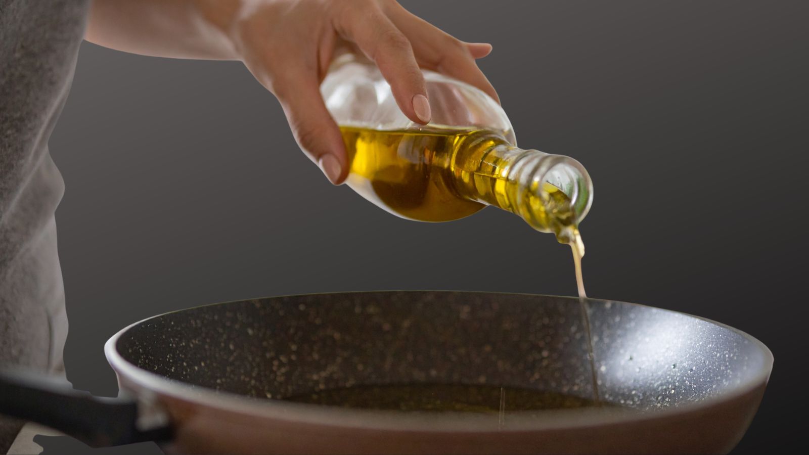 Kitchen Cupboard Staples, image of a mans hand pouring olive oil in to a frying pan on a dark grey background